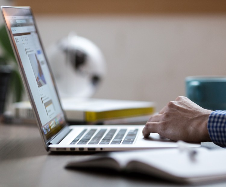 A person types on a laptop at a desk.