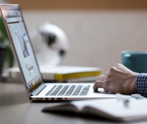 A person types on a laptop at a desk.